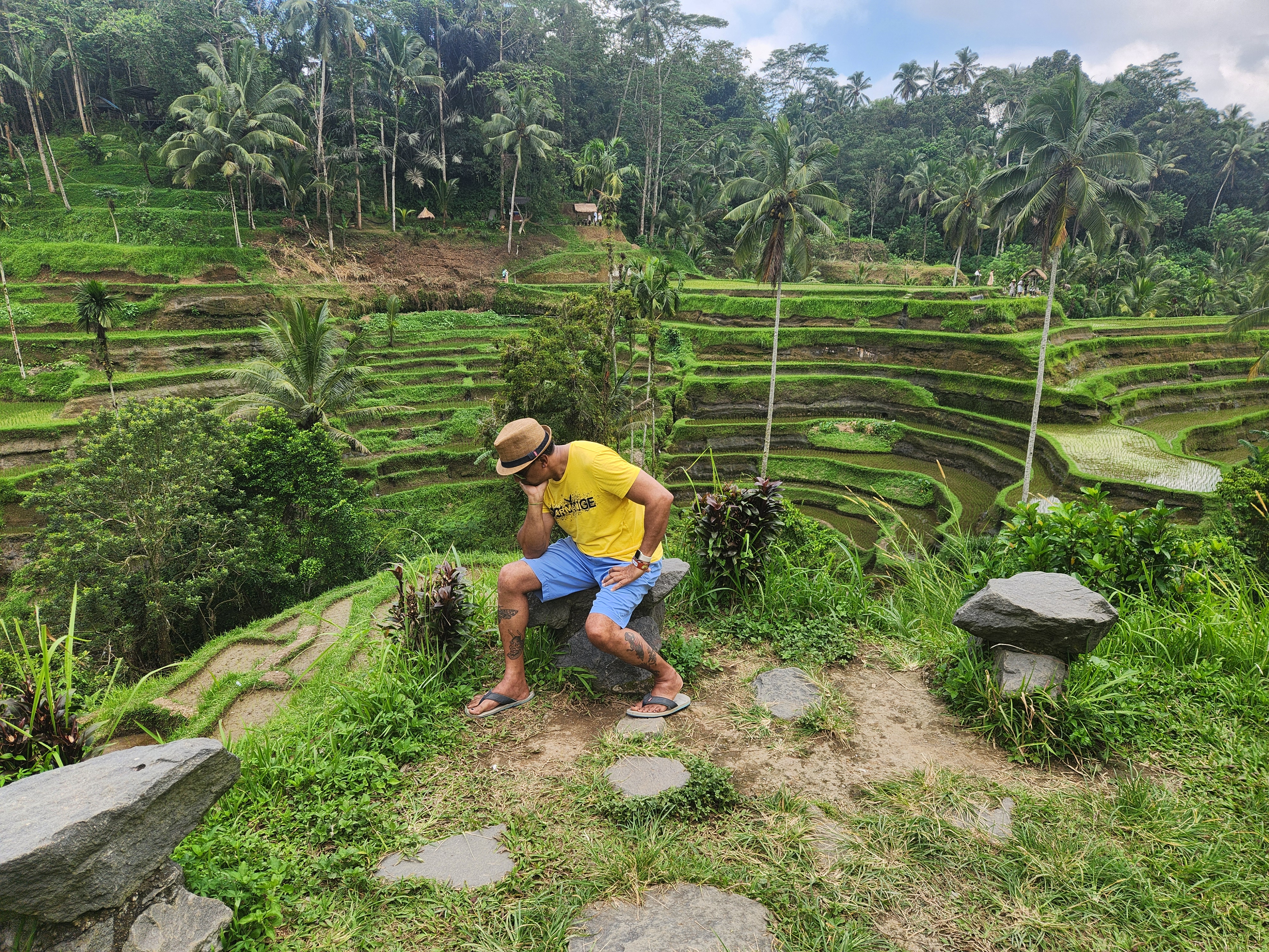 Visitor on a stone bench overlooking terraced rice paddies in Bali